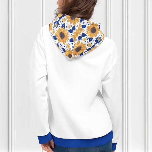A custom women's hoodie that is all white except for the waistband and the cuffs of the sweater are a bright blue in color, the front pocket and the hood of the sweater have a sunflower pattern that has blue inside the pattern that matches the waistband and the cuffs.