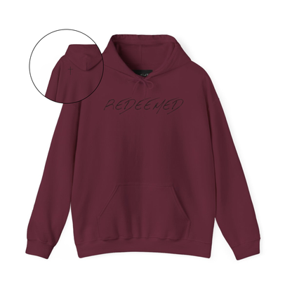 A maroon hoodie with the words redeemed on the front center, a Jesus cross is on the back left shoulder of the hoodie.