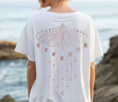 A woman modeling an oversized white washed T-shirt shown from both front and back. The front is plain, while the back features a large pale pink moon-phase dragonfly graphic.
