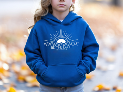 A blue youth hoodie with an image of the sun and waves underneath with the words Be the Light Matthew 5:14 