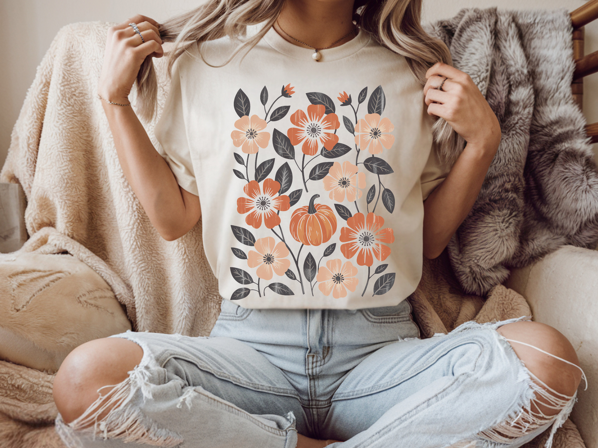 A graphic t-shirt with flowers and pumpkins all over the shirt, perfect for fall time.
