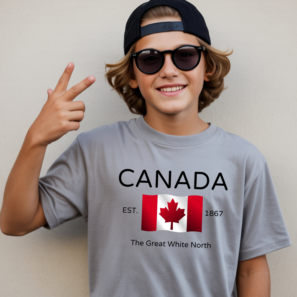 On the front of this youth t-shirt are the words Canada in large letters with a Canadian flag underneath, the letters Esrt1867 and the great white north are under the flag.