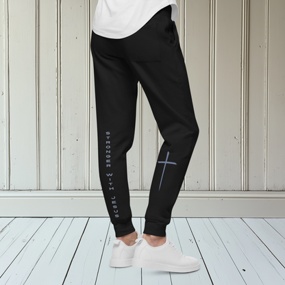A pair of fleece lined sweatpants that have the words Stronger With Jesus on the back left leg of the pants, on the right leg is a large Jesus cross