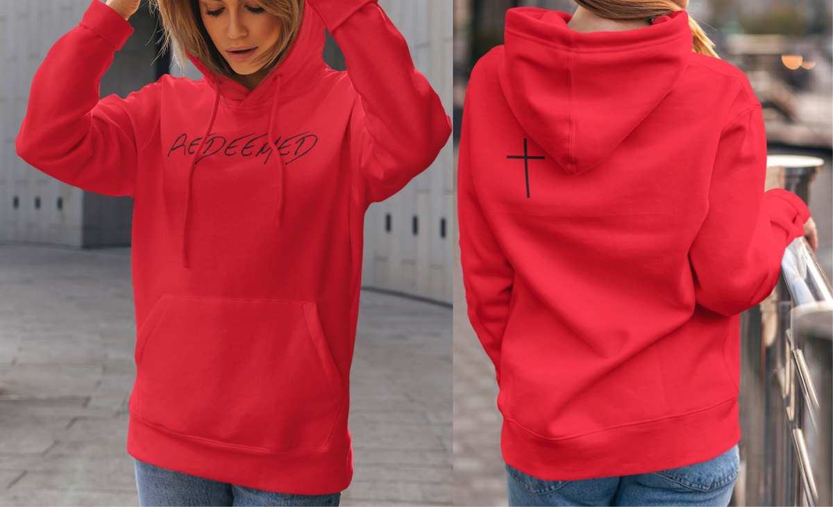 A red hoodie with the words redeemed on the front center, a Jesus cross is on the back left shoulder of the hoodie.