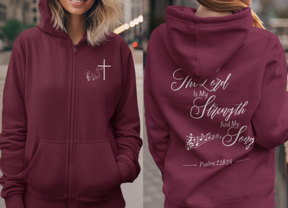On the front of this Christian zip up hoodie is an image of a Jesus cross with music notes coming from the top of the cross, on the back of the hoodie are the words 'The Lord is my strength and my song Psalms 118:14 with music notes on either side of the image.