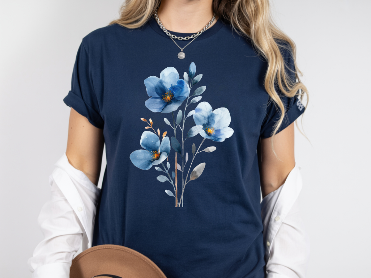 A woman wearing a navy blue short-sleeve t-shirt with a blue and white floral graphic on the front, styled with a white collared shirt underneath and a brown hat.