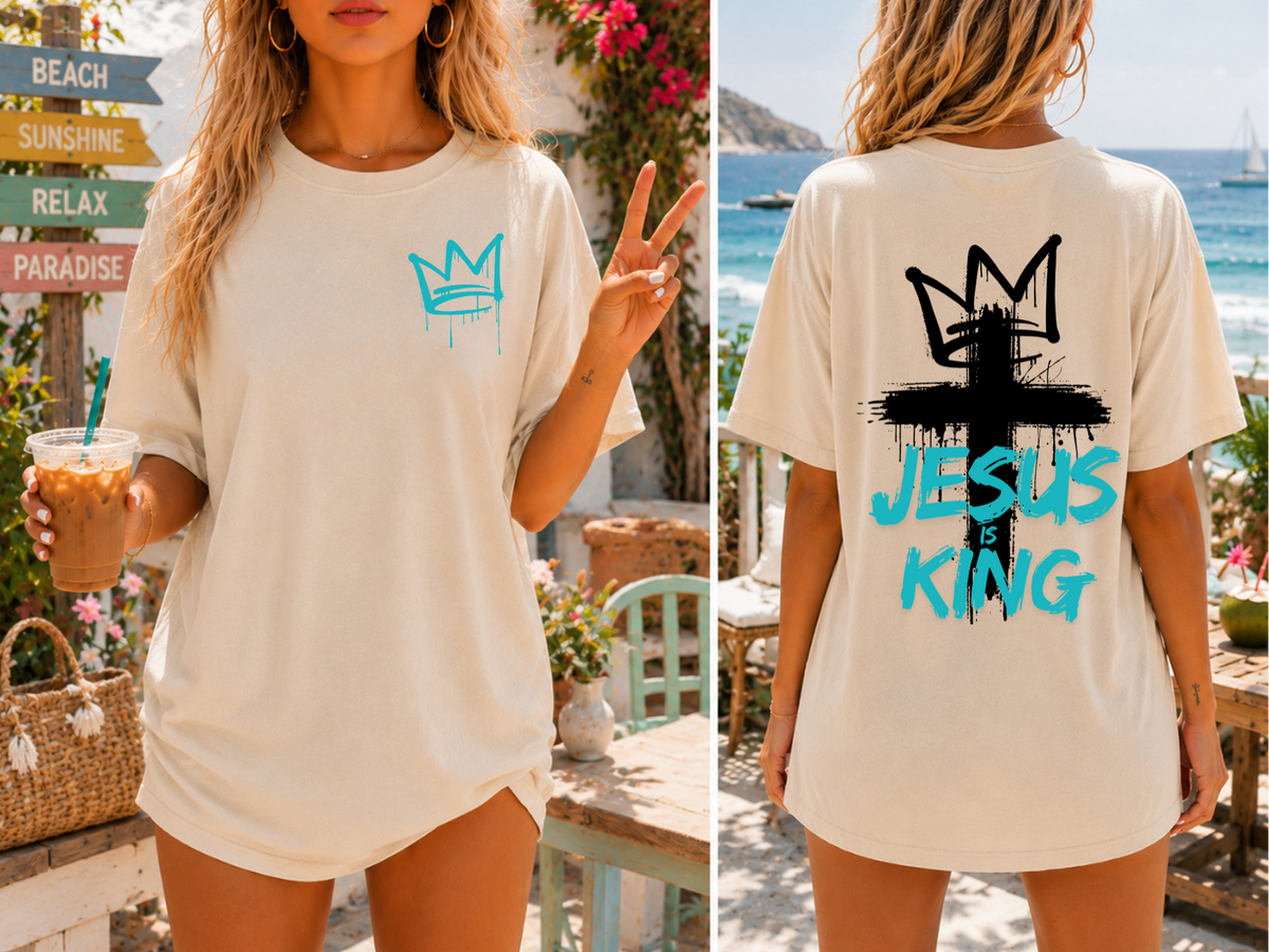 A oversized graphic t-shirt with an image of a crown spray painted on the top right chest of the shirt, on the back of the shirt is a large cross spray painted on the back with a cross on the top with the words 'Jesus is King' spray painted on the top.