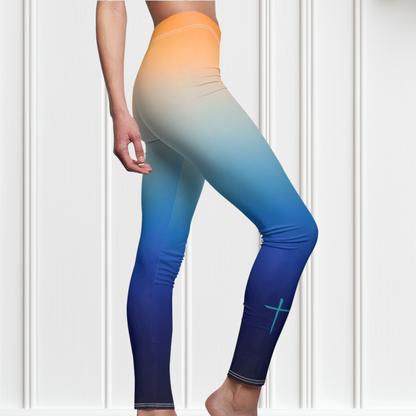 A pair of high waisted ombre leggings that start as a light orange then fade to a dark blue at the bottom, there is a light blue Jesus cross on the right ankle of the pants.