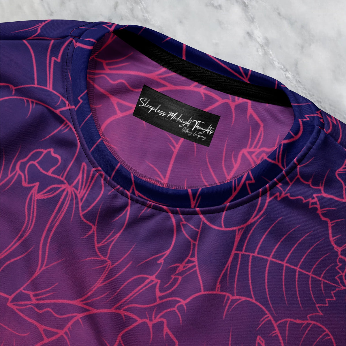 The sweater has a washed ombre pattern starting as a dark purple at the top of the neckline then fading to a light purple then to a bright pink then to a blush pink at the bottom, there is a purple floral pattern imposed on the top of the sweater.